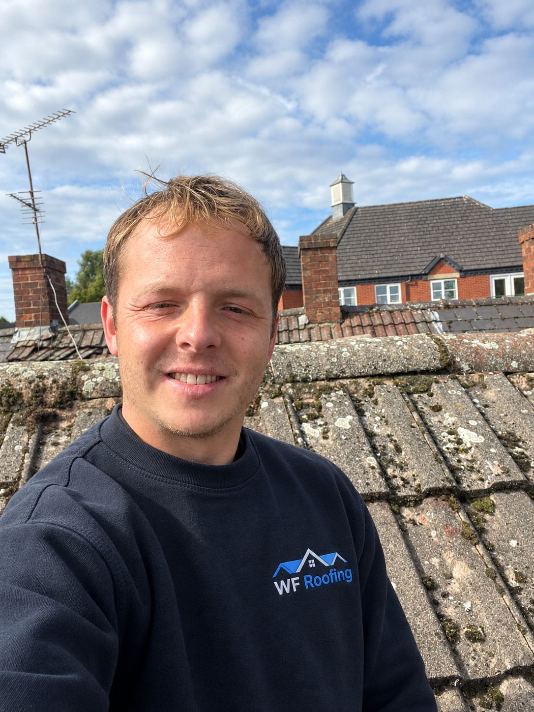 William, owner of WF Roofing, standing on a tiled roof in Cannock wearing the company sweatshirt